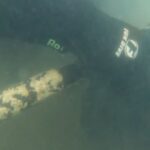 Policiais mergulhadores apreendendo fuzil de guerra submerso em litoral